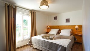 Una camera da letto con una testiera in legno, due abat-jour, un letto con copriletto trapuntato e una finestra con tende.
