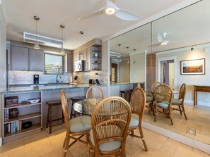 Een moderne keuken met een groot kookeiland, inbouwapparatuur en een eethoek met rieten stoelen.