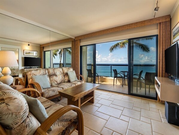 Een ruim balkon met uitzicht op de oceaan, voorzien van een bank, stoelen en een tafel.