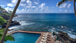 Ein Poolbereich mit Liegestühlen und Blick auf das Meer.