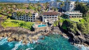 Ein Resort mit mehreren Gebäuden, einem Schwimmbad und einer felsigen Küstenlinie.