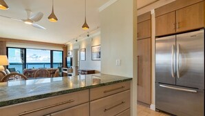 Eine moderne Küche mit einem großen, edlen Kühlschrank aus Edelstahl, Holzschränken und einer Arbeitsplatte aus Granit.