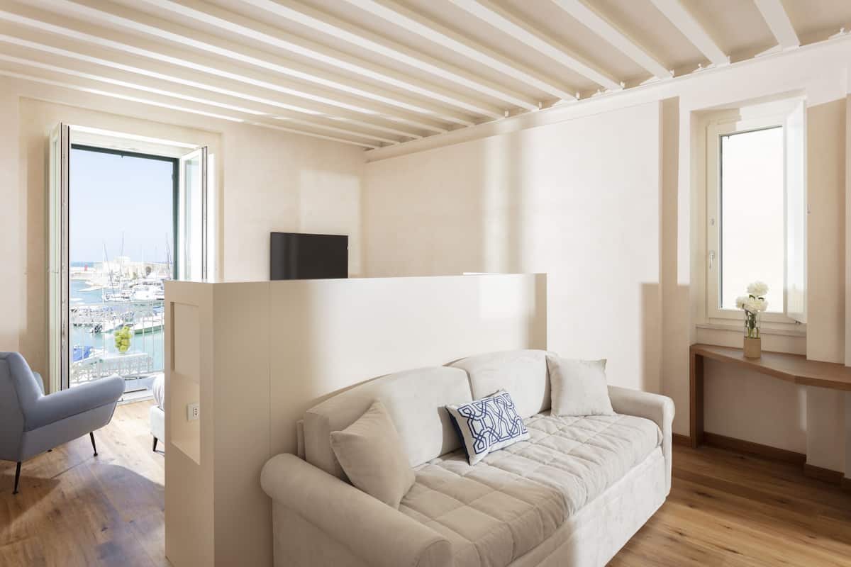 Una sala de estar moderna con un sofá color beige, un televisor montado en la pared y vistas de la marina a través de un ventanal grande.