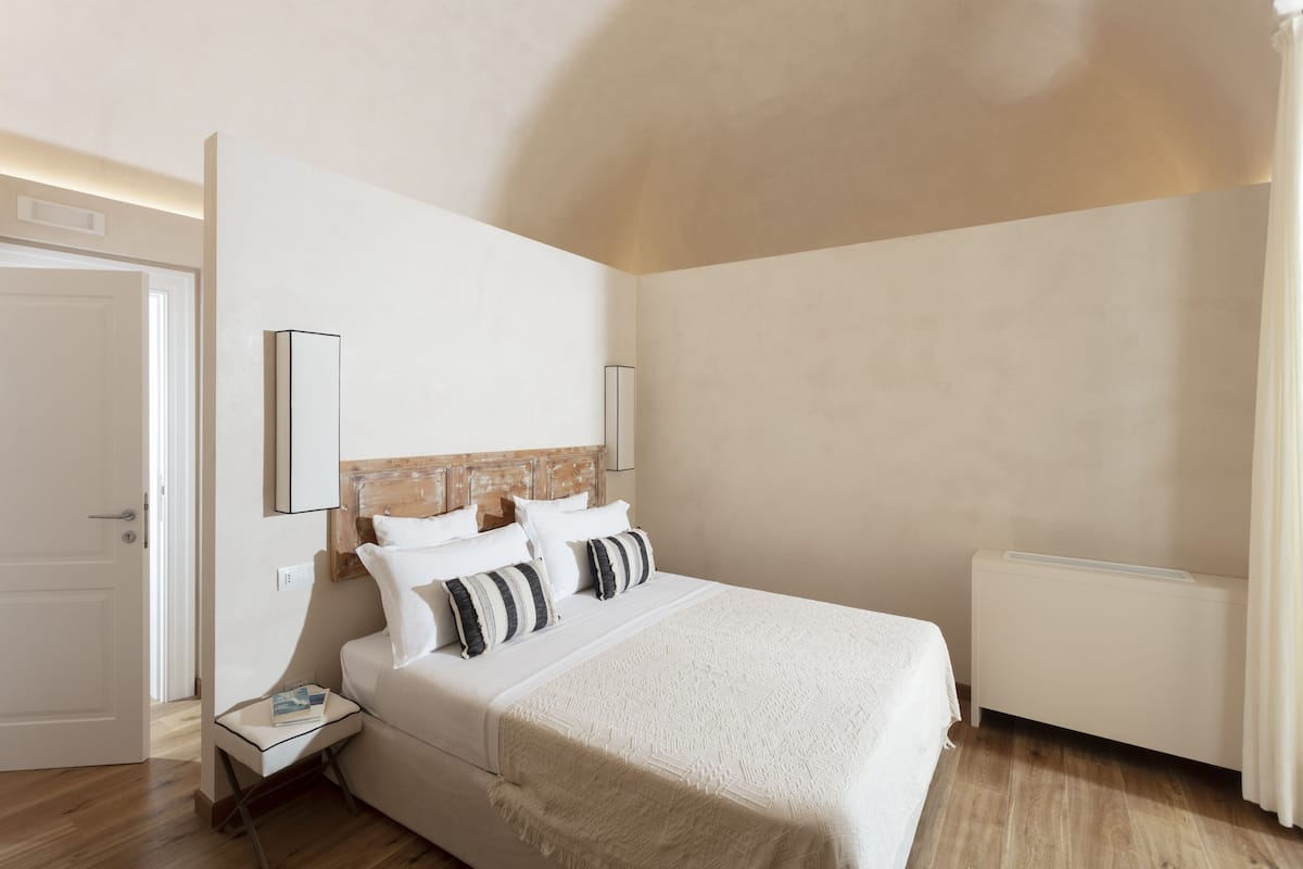 Un dormitorio con una cama grande, una mesita de noche, un radiador y un espejo en la pared.