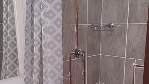 Un baño con ducha, lavamanos y azulejos estampados.