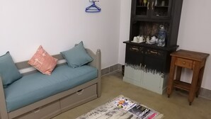 Una habitación con un sofá, un armario de madera y una pequeña mesa de madera.