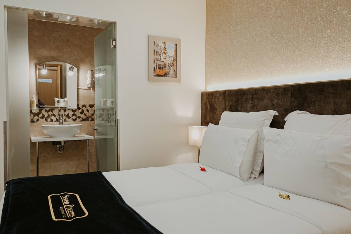 A hotel room with a bed, a bathroom with a sink and mirror, and a framed picture on the wall.