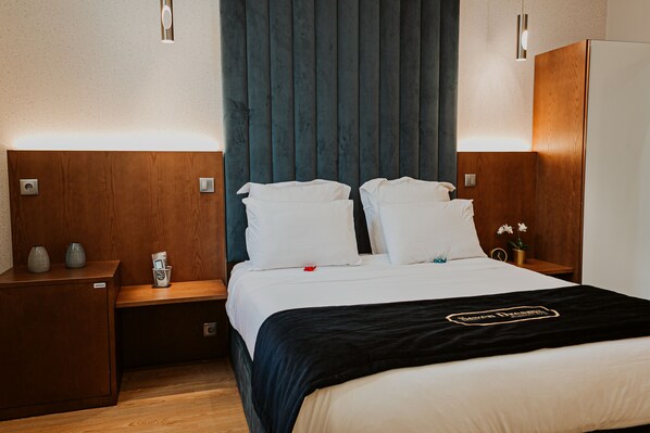 Une chambre d’hôtel avec un lit, des tables de chevet, une armoire en bois et un rideau bleu.