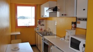 A compact kitchen with a window, a sink, a stove, and a microwave. - Studio sea view in Trégastel with private parking (Trégastel)