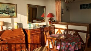 A dining area with a wooden table, chairs, a mirror, and a chandelier. - Studio sea view in Trégastel with private parking (Trégastel)