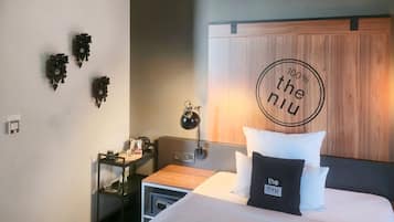 Una habitación de hotel con cama, mesita de noche, lámpara y decoración en la pared.