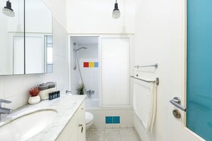 A bathroom with a white sink, a mirror, a towel rack, and a shower area.