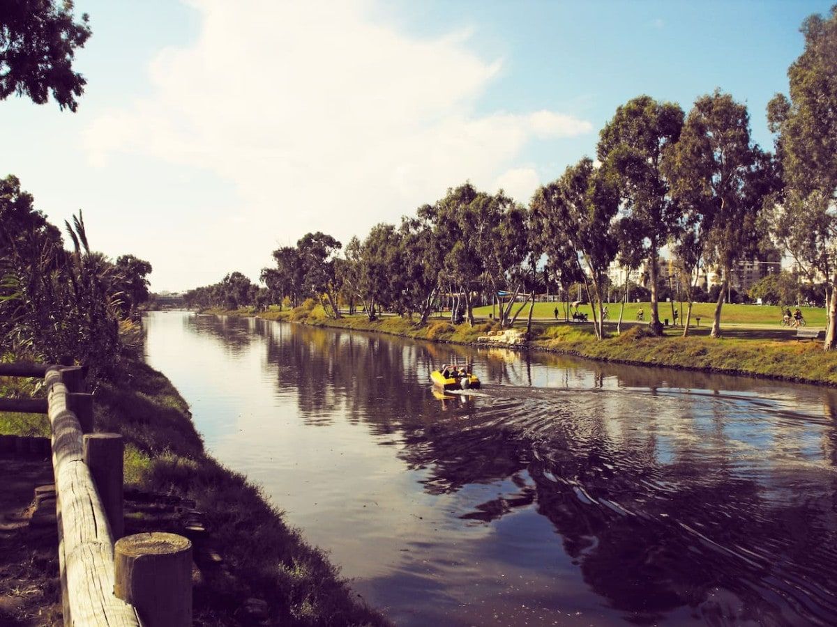 Un río tranquilo con una valla de madera a un lado y árboles al otro.