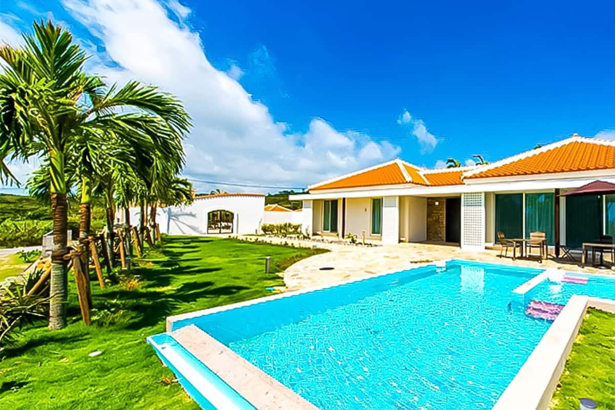 Ein modernes Haus mit Swimmingpool, Terrasse und Gartenmöbeln sowie einem gepflegten Rasen.