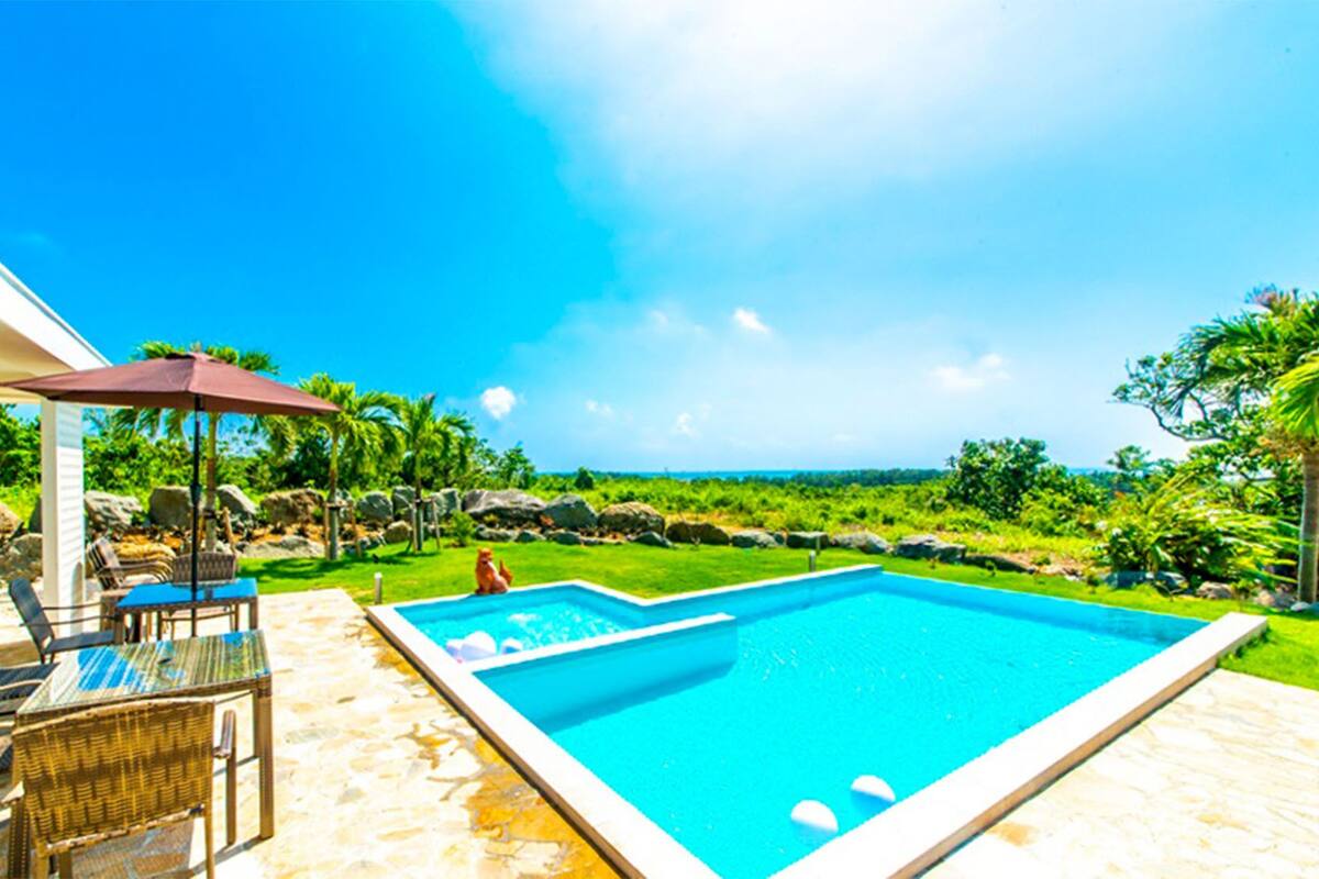 Ein Pool mit Meerblick, Gartenmöbel und eine überdachte Sitzgelegenheit.