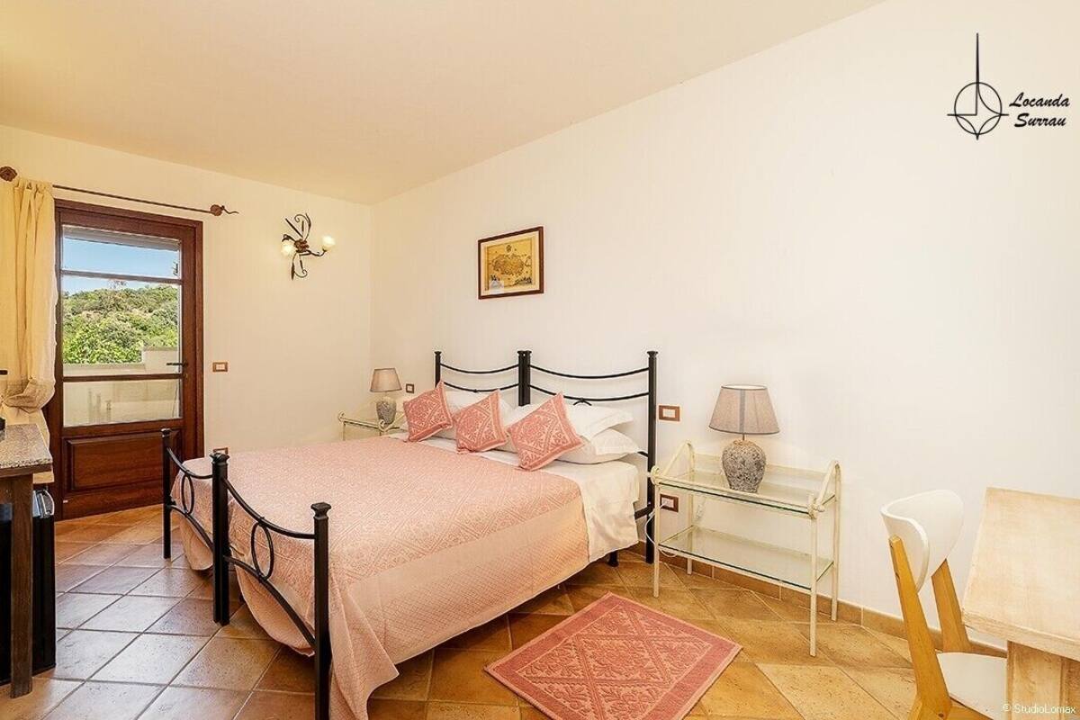A bedroom with a bed, bedside tables, a desk, and a window.