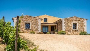 A stone house with a central entrance, two windows on the side, and a gravel driveway. - Locanda In Vigna (Arzachena)