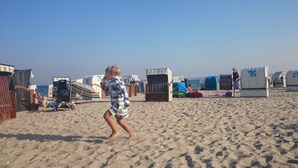 A sandy beach with beach huts numbered 26, 83, 16, and 21. - Pottkiekerhus (Luhnstedt)