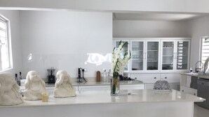 Une cuisine moderne avec des meubles blancs, un îlot central et un vase rempli de fleurs blanches.