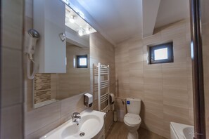 Un baño moderno con lavamanos, espejo, toallero, inodoro y una ventana pequeña.