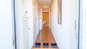 Een gang met een houten vloer en een rij schoenen aan het einde.