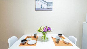Een eettafel gedekt met borden, kommen en een bloevas, met een schilderij aan de muur erboven.