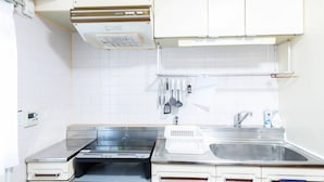 Een keuken met witte kasten, een roestvrijstalen spoelbak en een inbouwoven.