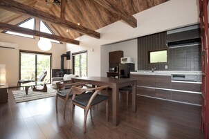 Una cocina moderna con armarios de madera, un comedor con mesa de vidrio y un amplio ventanal que proporciona luz natural.