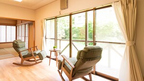 A room with two rocking chairs, a small table with a plant, and large windows with curtains. - GrandTree Hakone Sengokuhara (Hakone)