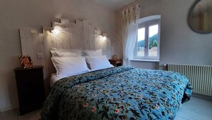 Un dormitorio con cama, mesita de noche y radiador, además de una ventana.