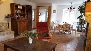 Una sala acogedora con un aparador de madera, un sillón rojo, una mesa de comedor con sillas y una araña.