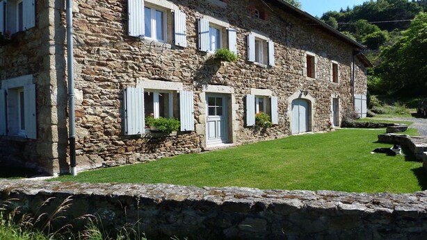 Un edificio de piedra con múltiples ventanas y un césped bien cuidado.