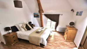 Une chambre à coucher avec un lit, des tables de chevet en bois, une commode et une fenêtre avec des rideaux.