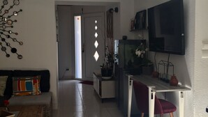 Un vaste espace de vie comprenant un canapé, une table basse et un téléviseur fixé au mur.