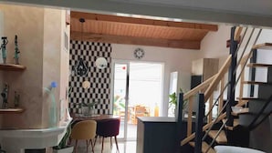 Un salon moderne avec un escalier, un coin repas avec des chaises et un mur à carreaux.
