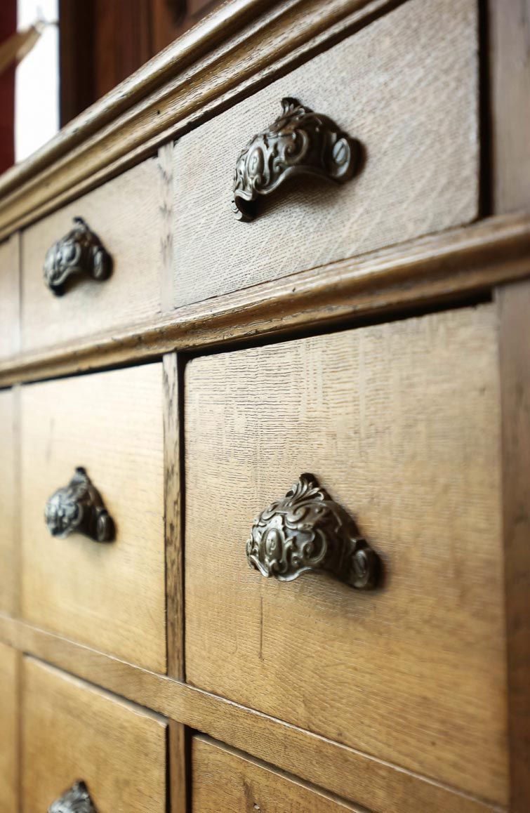 A wooden dresser with ornate metal handles.