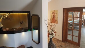 A reception area with a counter, a mirror, a vase with flowers, and a painting on the wall. - Dom Wczasowy Barbara (Wladyslawowo)