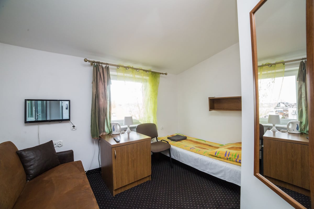 A hotel room with a bed, a desk, a chair, a television, and a window with curtains.