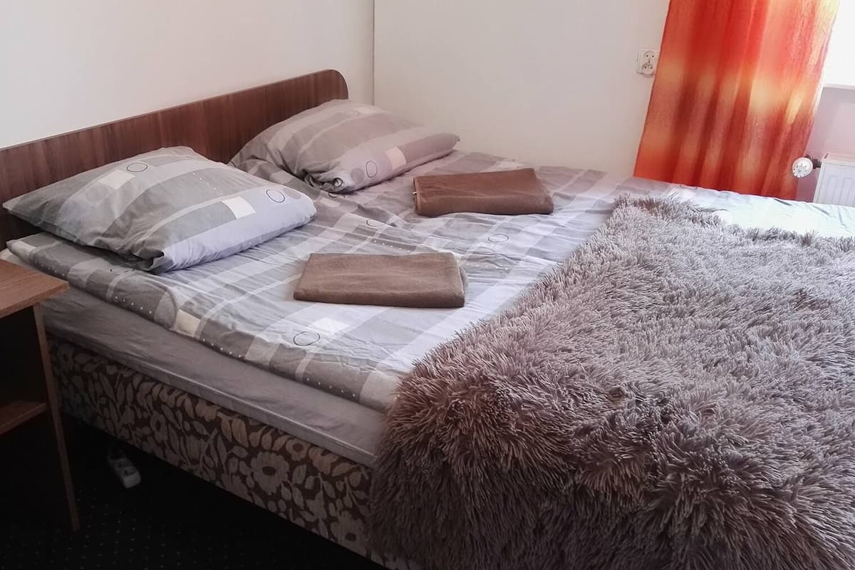 A neatly made bed with a checkered bedspread, two pillows, and a fluffy brown throw.