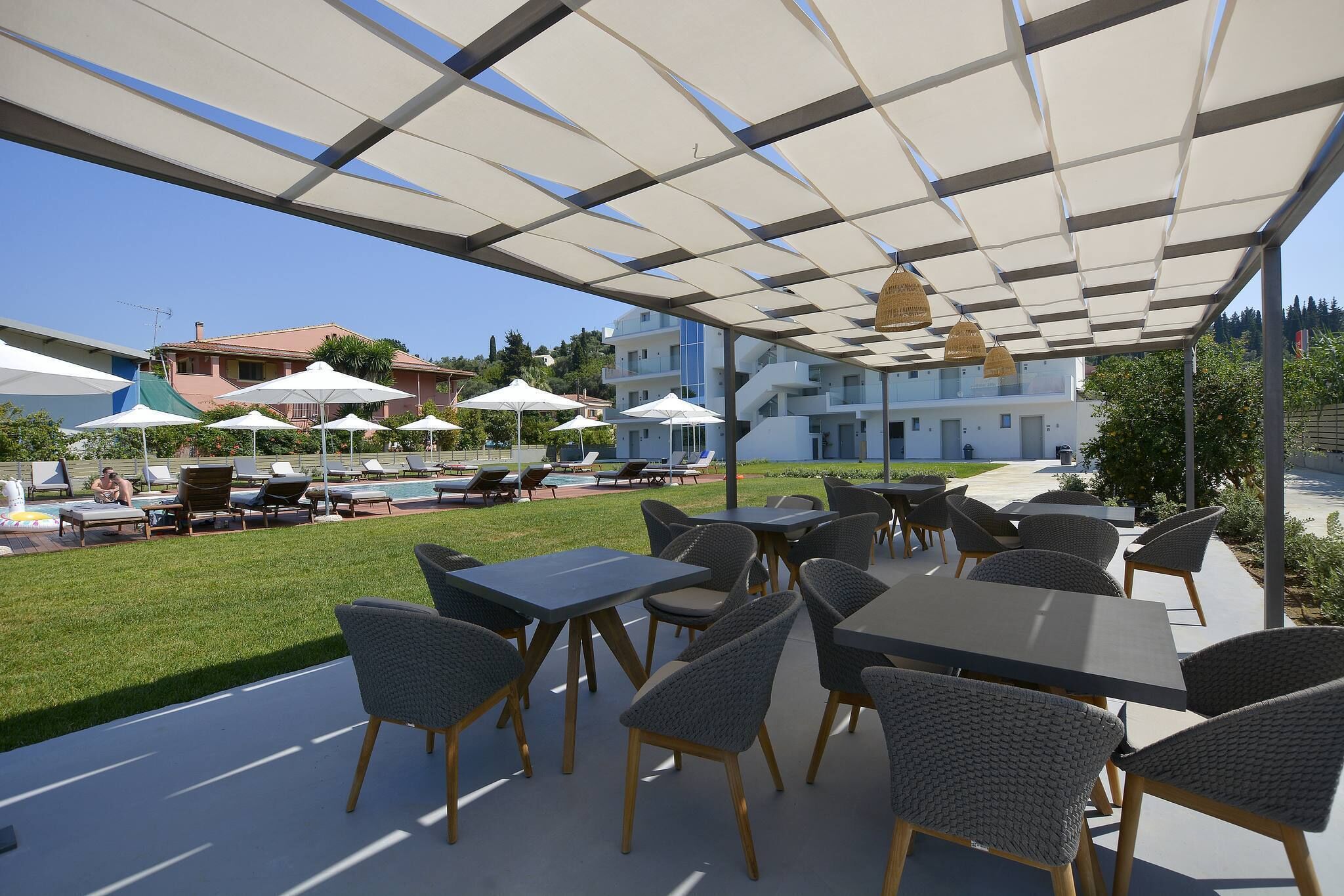 An outdoor patio area with tables and chairs, a pool, and a view of buildings in the background.