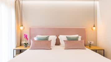 A neatly made bed with a pink headboard, two bedside tables with lamps, and a potted orchid on the left side.