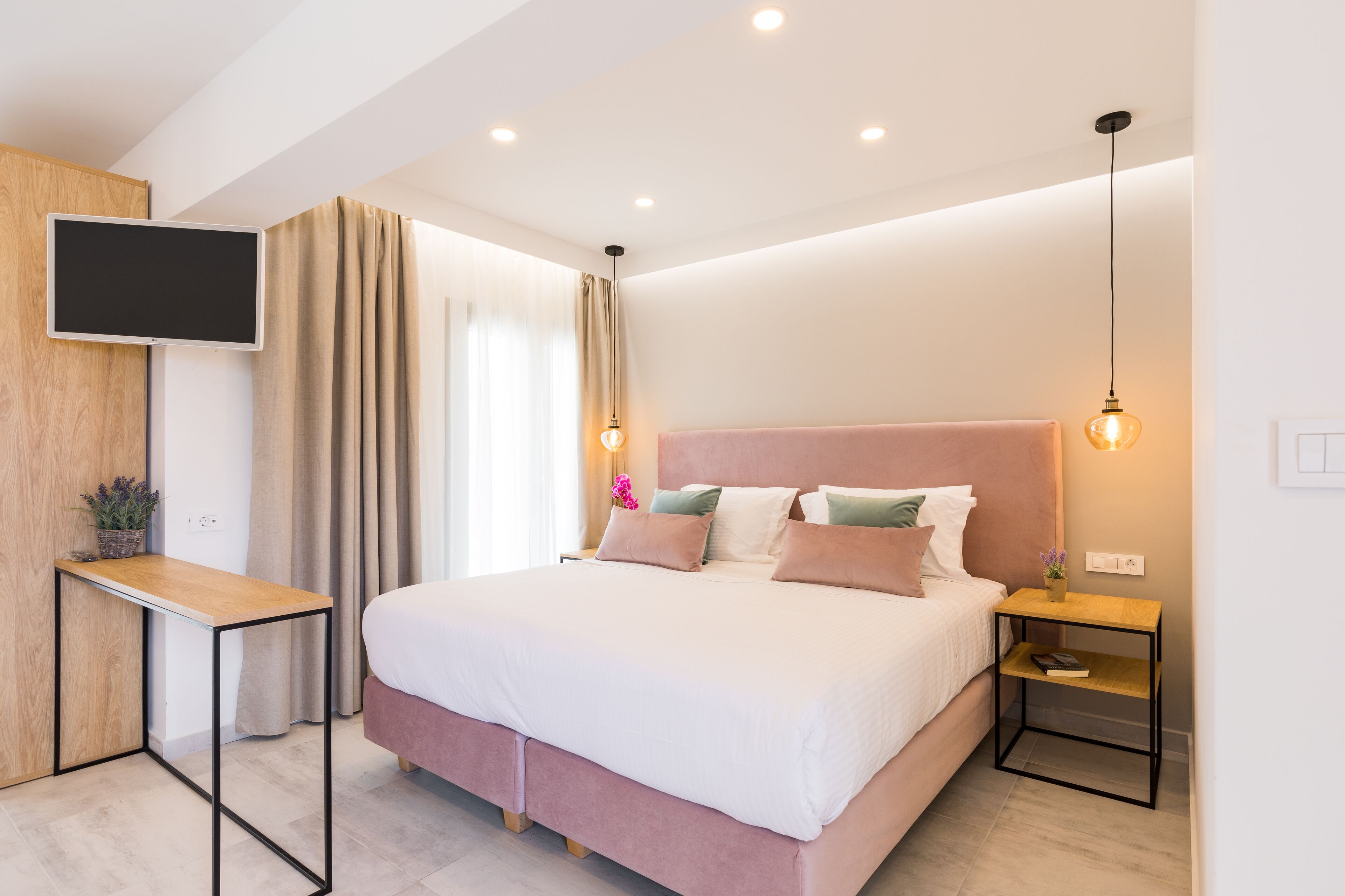 Une chambre moderne avec un lit, des tables de chevet, une télévision et une fenêtre avec des rideaux.