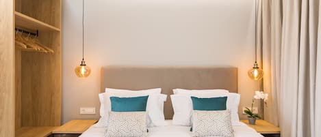 A neatly arranged hotel room with a large bed, two bedside tables, a wooden wardrobe, and a hanging light fixture.