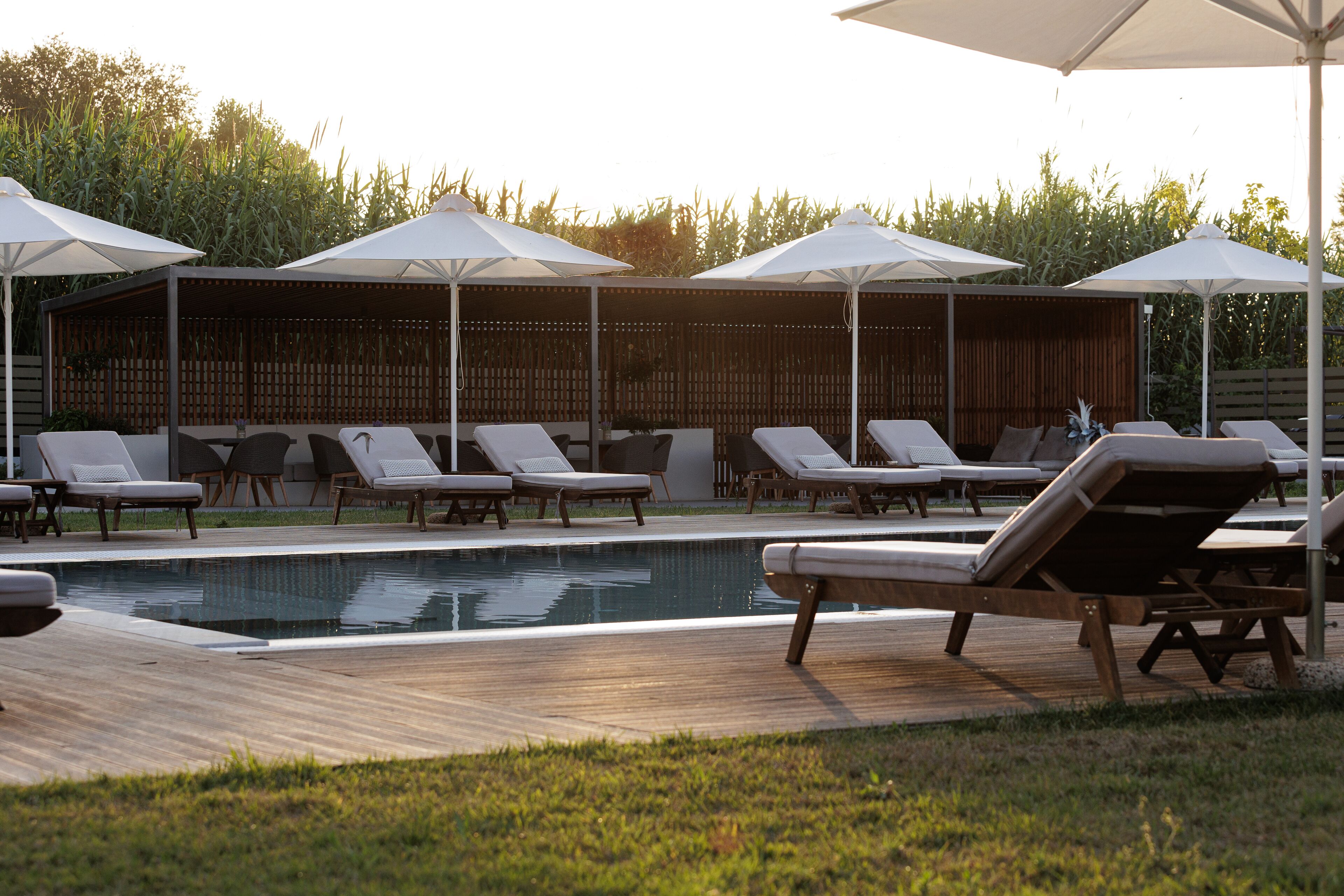 A pool area with lounge chairs and umbrellas.