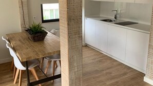 Een moderne keuken met witte kasten, een houten eettafel met stoelen en een hanglamp.