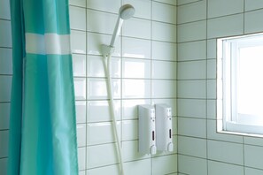 A bathroom with white tiled walls, a shower with a white hose, and a window with a white frame. - Yeah B&B (Tainan)