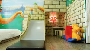 Ein Kinderspielbereich mit Rutsche, einem Schaukelpferd und Wandgemälde.