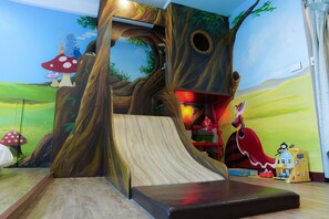 A play area with a slide, a tree mural, and a character painting. - Yeah B&B (Tainan)