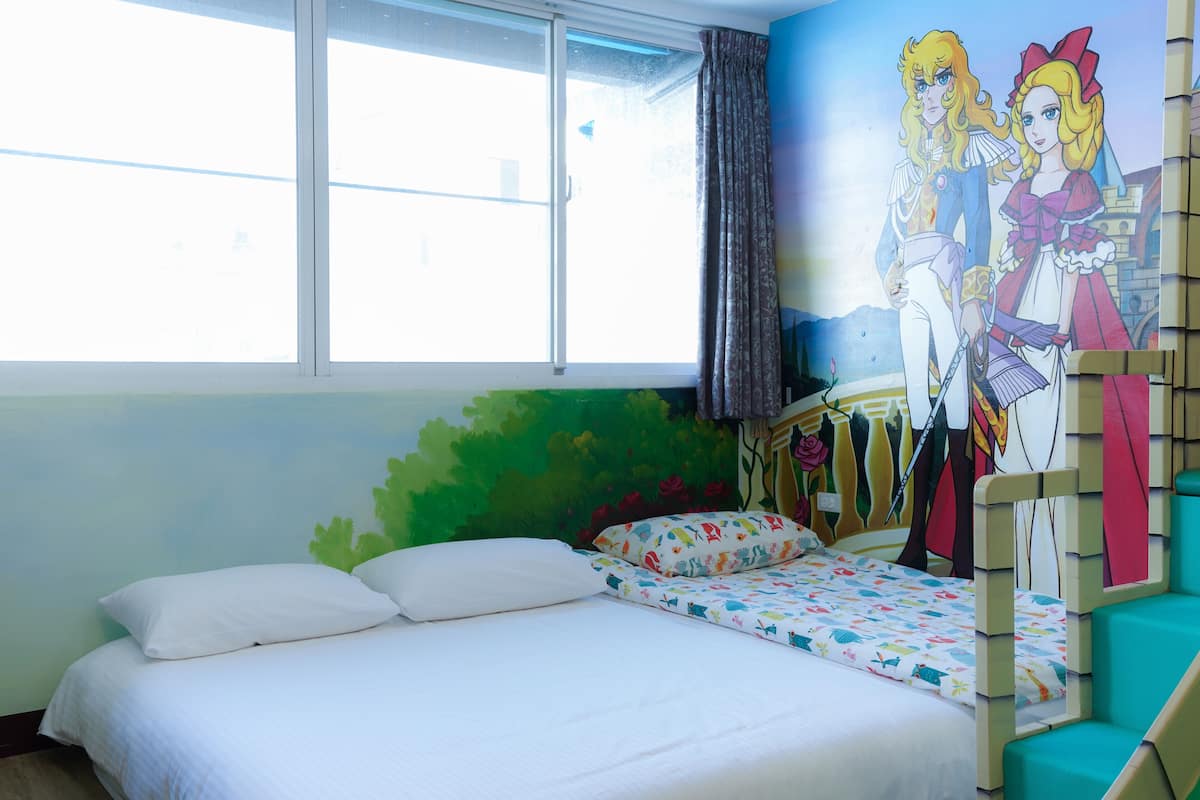 A bedroom with a bed, a window, and a mural on the wall.