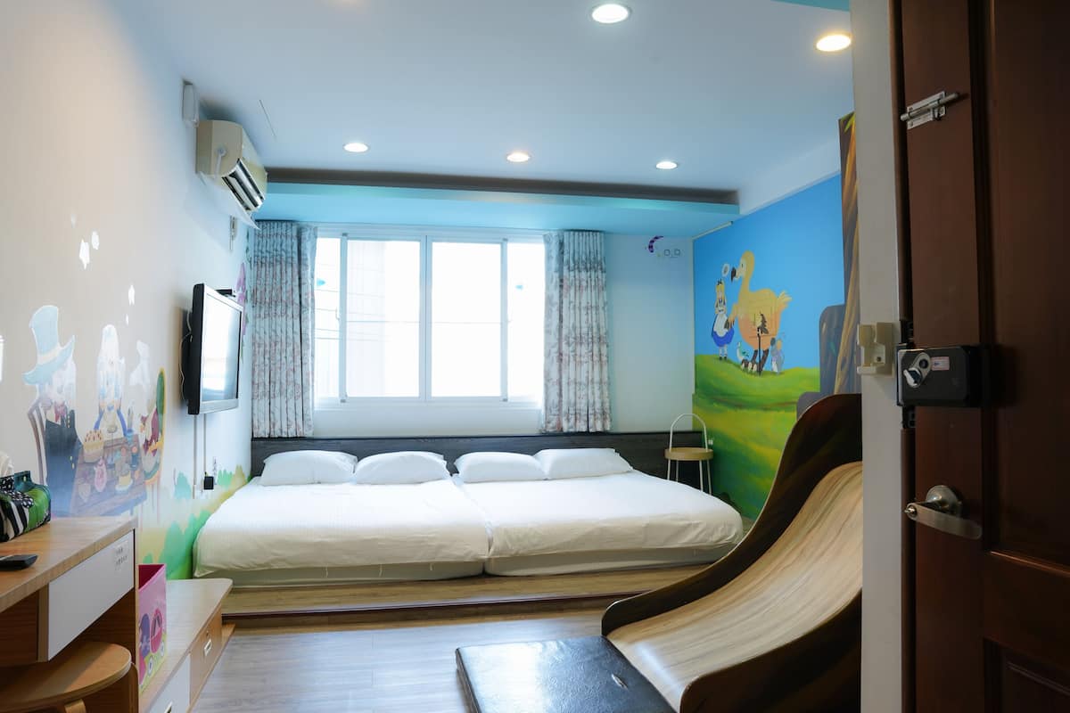 A bedroom with a bed, a desk, a chair, and a window with curtains.